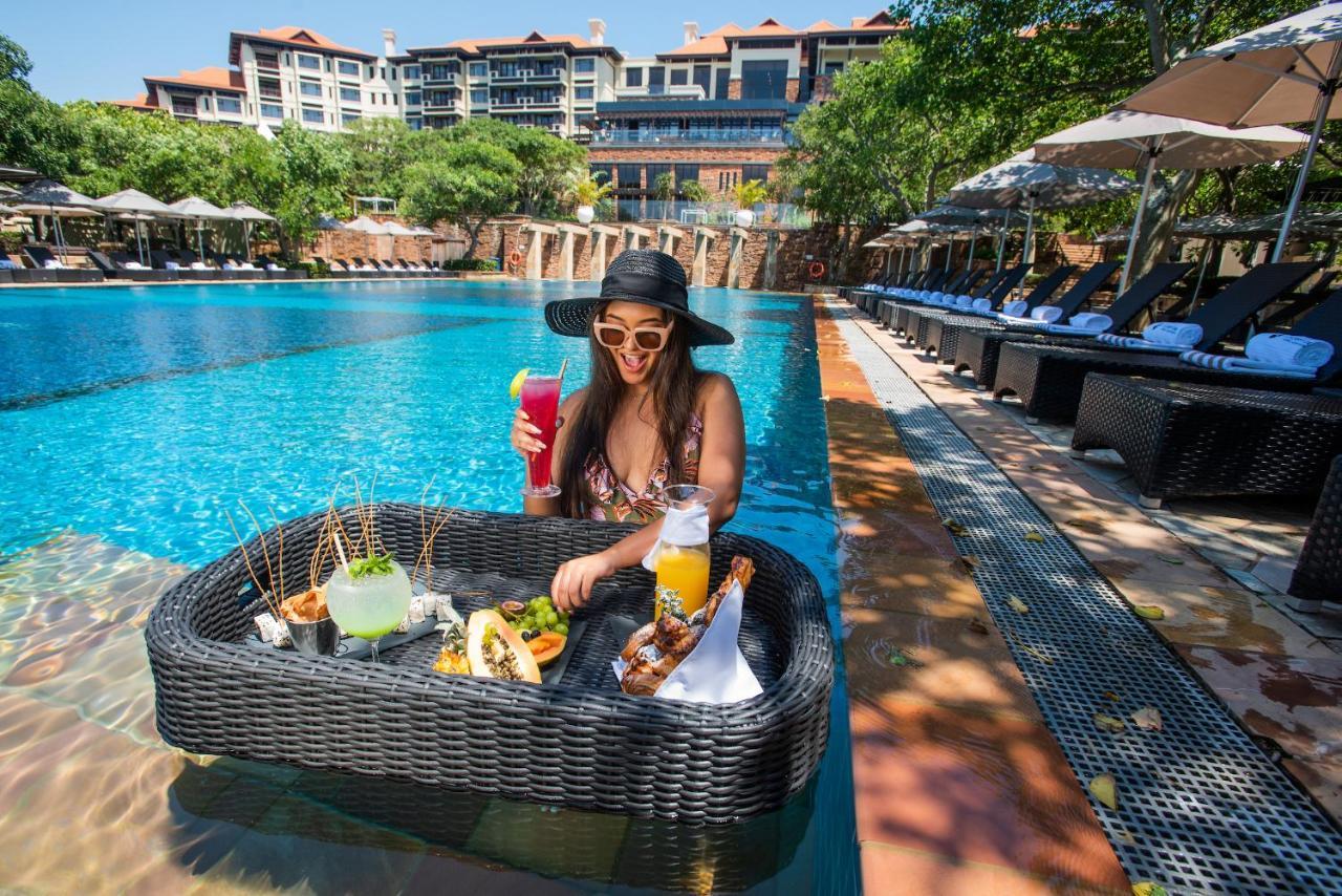 Hotel The Capital Zimbali Ballito Exterior foto A woman at a poolside lounge